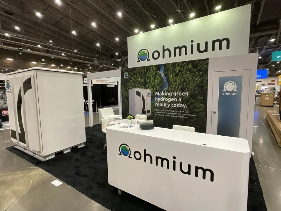 Ohmium exhibit with white reception counter and overhead sign